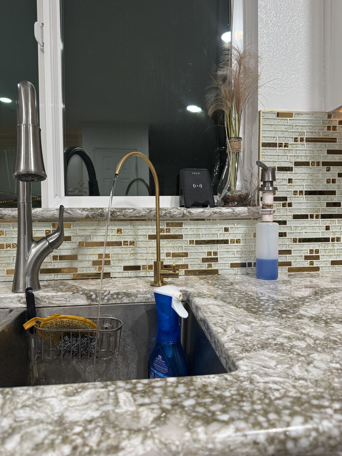 Gold reverse osmosis drinking water faucet running at a kitchen sink